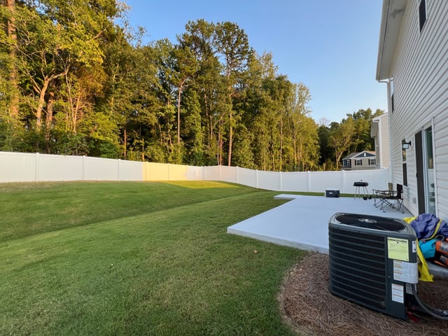Mowed backyard lawn running along a white vinyl fence