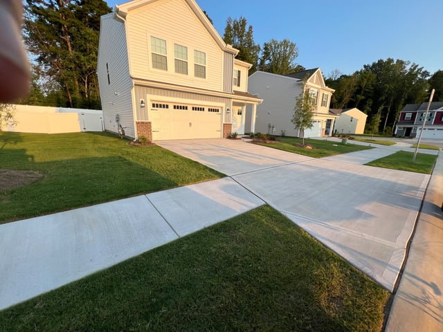 Freshly mowed front lawn beside the driveway of a two-story home